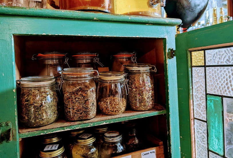Glass clip-top jars of dried herbs on a timber shelf