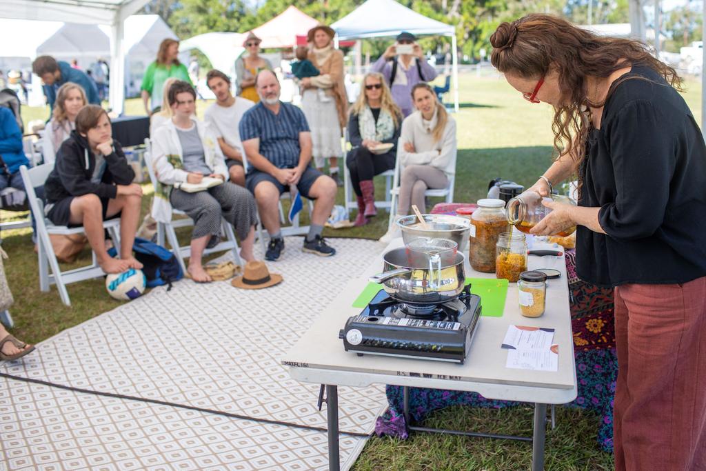 Herbalist demonstrating calendula oil making at HerbFest with an engaged crowd watching